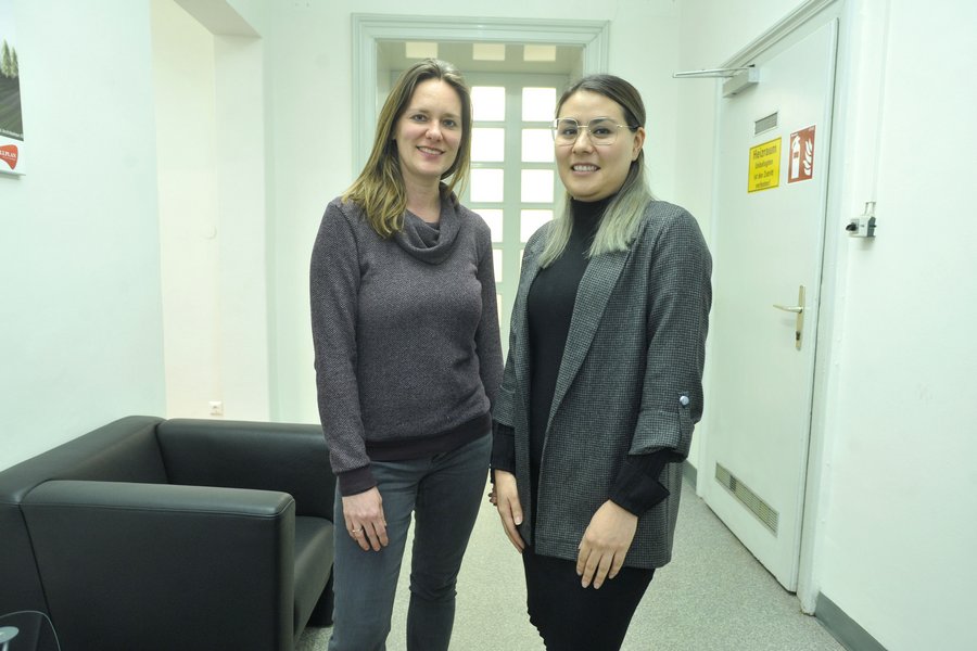 Zwei junge Frauen, eine davon mit Brille, in Büroräumlichkeiten.