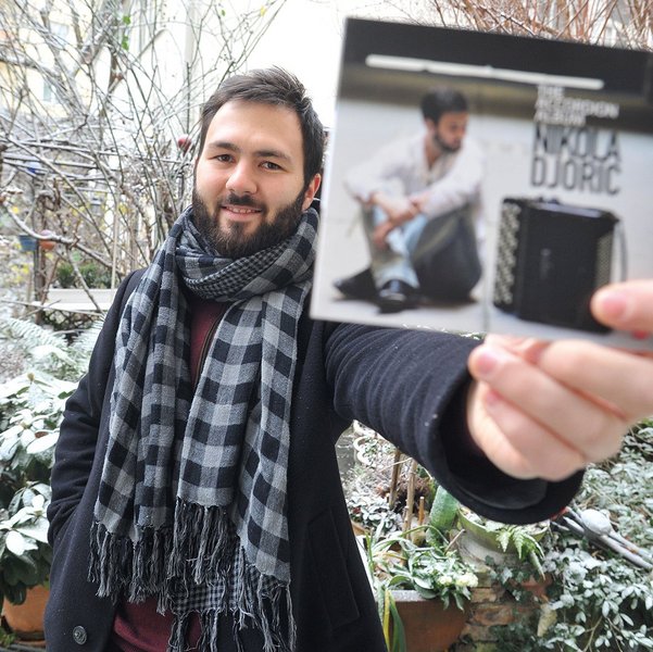 Nikola Djoric, ein bärtiger, dunkelhaariger junger Mann hält seine CD in die Kamera
