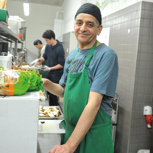 Ein freundlich lächelnder Mann mit grüner Küchenschürze